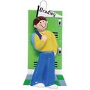 The Holiday Aisle® Teenage College/School Boy Hanging Figurine Ornament Plastic in Green/Red/Yellow | 4.25 H x 2.25 W x 0.5 D in | Wayfair